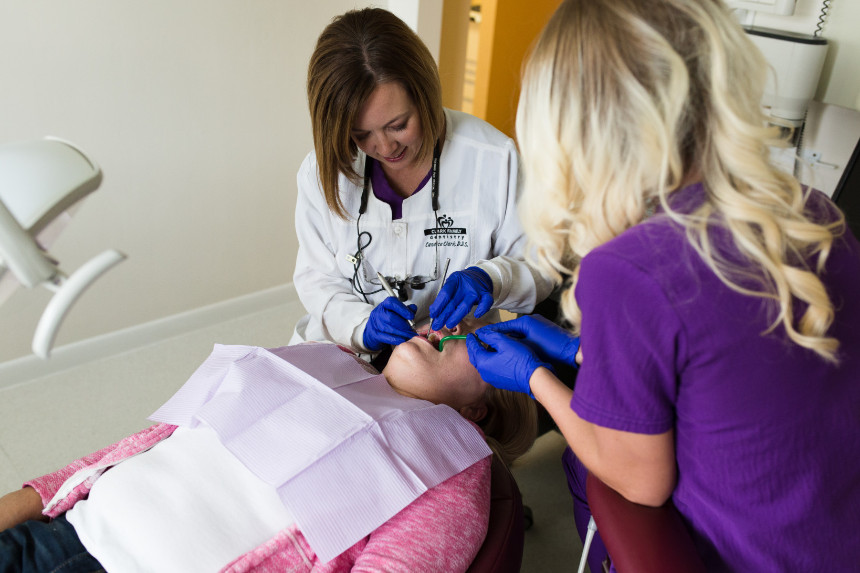 A dental professional is assisting a patient with a device that appears to be measuring the airway during a dental appointment.