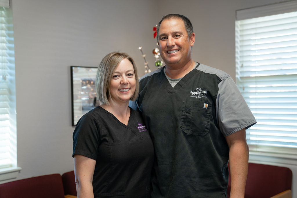 A man and a woman, both in scrubs, standing together in an office setting.